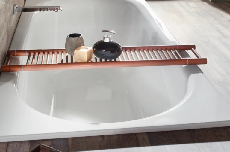 Baignoire rectangulaire en acier émaillé, blanc brillant, avec tablette en bois et accessoires de salle de bain, dans une salle de bain moderne.